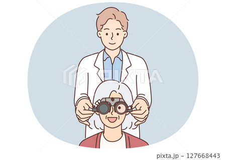 Man optometrist putting on ophthalmic glasses on elderly female patient during vision treatment 127668443