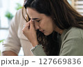 Supportive couple in emotional moment at home as woman struggles with sadness and stress, expressing 127669836