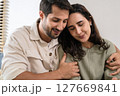 Supportive couple in emotional moment at home as woman struggles with sadness and stress, expressing 127669841