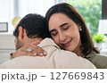 Supportive couple in emotional moment at home as woman struggles with sadness and stress, expressing 127669843