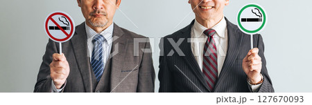 喫煙マークと禁煙マークを持つミドルエイジ男性ビジネスパーソンのグループ 127670093