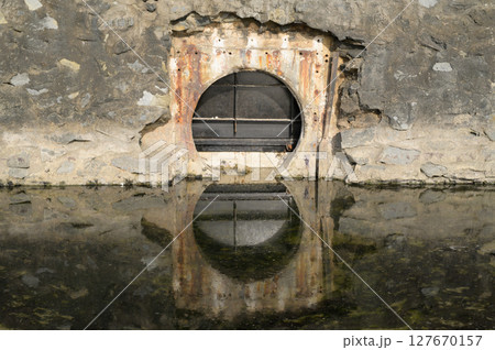 steel floodgate and concrete wall.Waste water is in front of steel floodgate. 127670157
