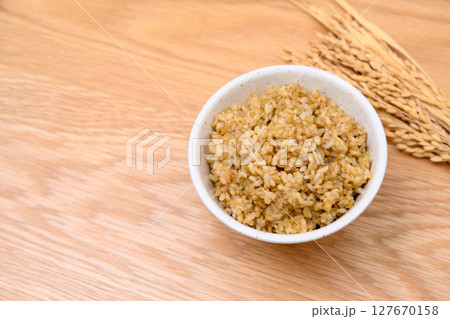 木目テーブル背景の茶碗に玄米ごはんと稲穂 木目テーブル背景の茶碗に玄米ごはんと稲穂 127670158