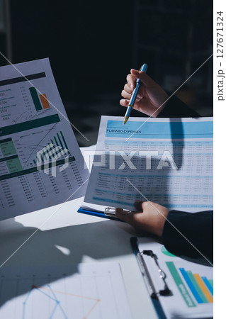 Group of business women working on a financial data expenses document. Group of business women working on a financial data expenses document. 127671324