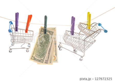 Two miniature shopping carts hung on a clothesline with colorful clothespins Two miniature shopping carts hung on a clothesline with colorful clothespins 127672325