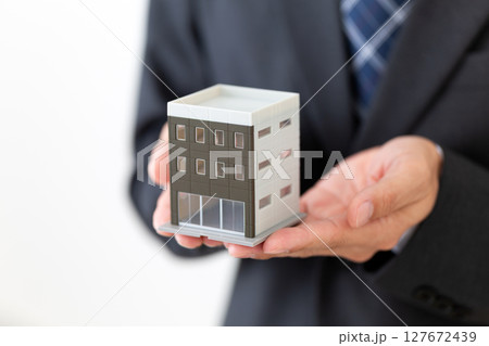 ビルの模型を持つスーツ姿のミドル男性ビジネスマン 127672439