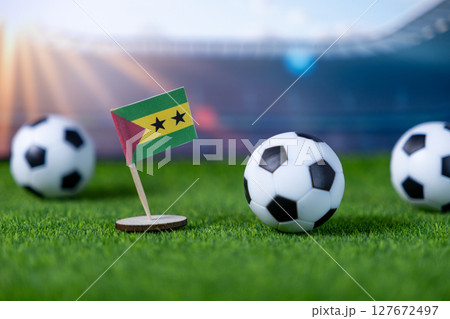 Sao Tome and Principe flag stands on a vibrant green football pitch with balls, symbolizing national pride and international sports event 127672497