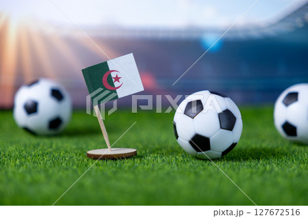 Algerian flag with soccer balls on green grass, symbolizing national pride, international football competition, and championship spirit 127672516