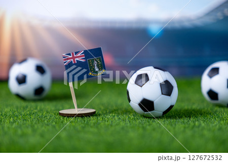 British Virgin Islands flag and soccer balls on green field, representing international football competition and national sports pride in a stadium setting 127672532