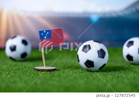 Miniature Samoa national flag with soccer balls on vibrant green grass, symbolizing international sports competition, global unity, and team spirit 127672545