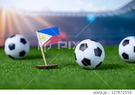 Miniature Philippines flag and soccer balls on green stadium grass, symbolizing international football championships, national team pride, and sports events 127672558