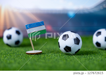 Uzbekistan flag and soccer balls on green grass, symbolizing national pride, team spirit, and global sports competition in a stadium Uzbekistan flag and soccer balls on green grass, symbolizing national pride, team spirit, and global sports competition in a stadium 127672615