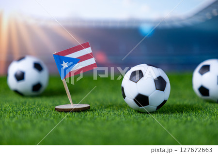 Vibrant Puerto Rico flag and miniature soccer balls resting on lush green stadium grass, embodying national team spirit and international sports competition 127672663