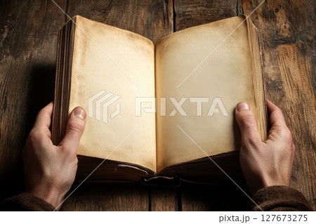 A person is holding an open book with a blank page 127673275