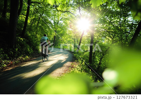 Serene Forest Cycling Journey, Eco-Friendly Transportation Concept with Sun-Dappled Path and Cyclist in Motion, Nature Adventure Background 127673321