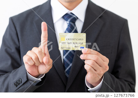 クレジットカードを持って人差し指を立てるスーツ姿のビジネスマン男性 127673766