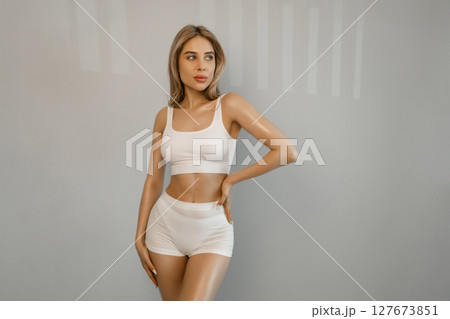 Perfect shape of belly, hips. Beautiful body of young slim woman in white underwear isolated on gray studio background. Wellness, weight loss, treatment, healthcare, fitness concept. Flyer 127673851