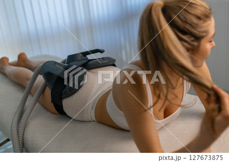 Woman getting treatment on buttocks to burn fat, build muscles and remove cellulite. Professional beauty salon Woman getting treatment on buttocks to burn fat, build muscles and remove cellulite. Professional beauty salon 127673875