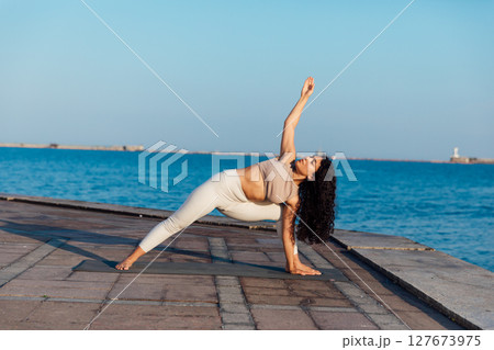 Athletic woman doing gymnastics yoga asana on the beach by the sea Athletic woman doing gymnastics yoga asana on the beach by the sea 127673975