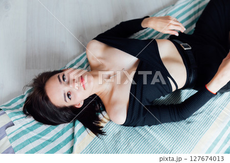 Slim fashionable woman in black clothes lying on mattress 127674013