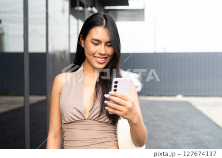 Modern Asian Woman Using Phone Outdoors in City 127674137