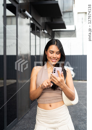 Modern Asian Woman Using Phone Outdoors in City 127674138