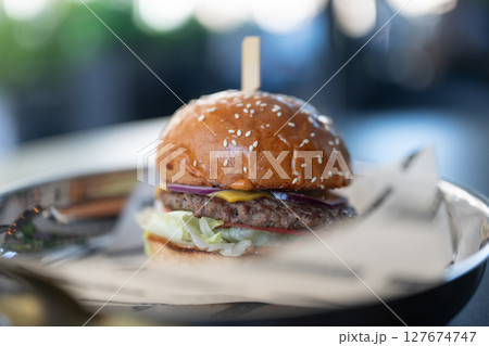 Delicious hamburger with melted cheese sitting on metal plate 127674747