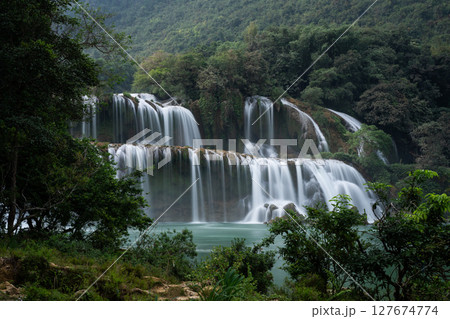 Detian Falls cascading water flowing through lush green vegetation in Vietnam 127674774