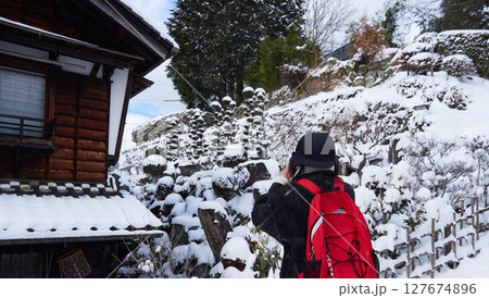 冬の中山道の観光名所馬籠宿の雪景色を撮影する若い女性観光客 127674896