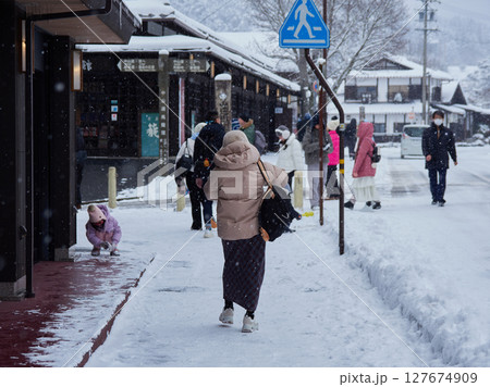 冬の中山道の観光名所馬籠宿の古い町並みの雪景色と観光客の姿 冬の中山道の観光名所馬籠宿の古い町並みの雪景色と観光客の姿 127674909