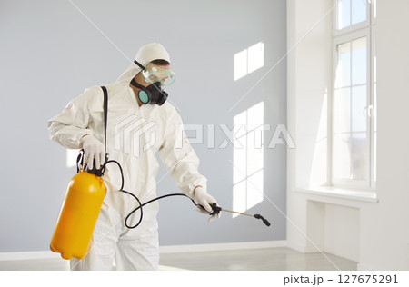 Disinfection worker in protective suit and mask disinfecting room with sprayer for pest control. Disinfection worker in protective suit and mask disinfecting room with sprayer for pest control. 127675291
