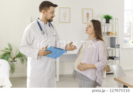 Pregnant woman talking with her gynecologist doctor during medical exam in clinic. Pregnant woman talking with her gynecologist doctor during medical exam in clinic. 127675310