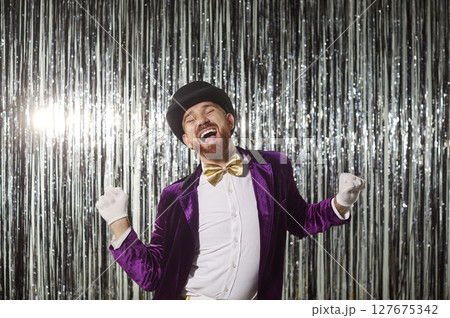 Excited funny showman dancing at disco party on shiny silver foil background Excited funny showman dancing at disco party on shiny silver foil background 127675342