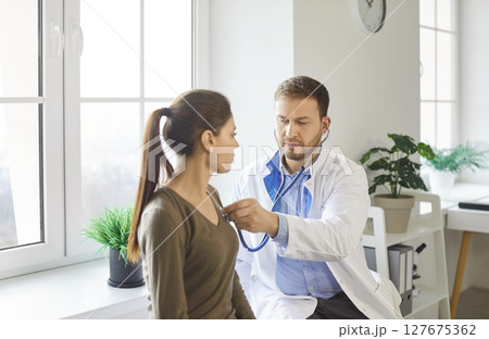 Focused Doctor Examining Patient With Stethoscope 127675362