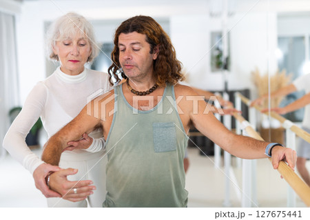 Elderly woman and adult man practicing ballet at barre Elderly woman and adult man practicing ballet at barre 127675441