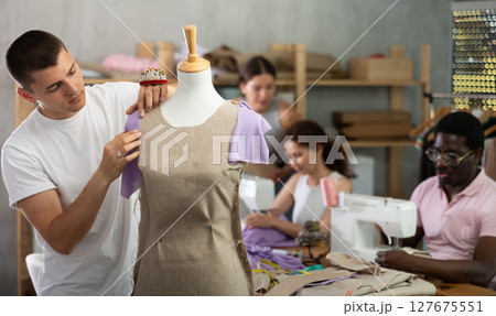 Young man working with mannequin in workshop 127675551
