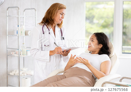 Professional beauty specialist giving documents to patient 127675568