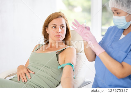 Anesthesiologist doctor injecting pain medication into vein of woman before starting surgery in cosmetology clinic Anesthesiologist doctor injecting pain medication into vein of woman before starting surgery in cosmetology clinic 127675587