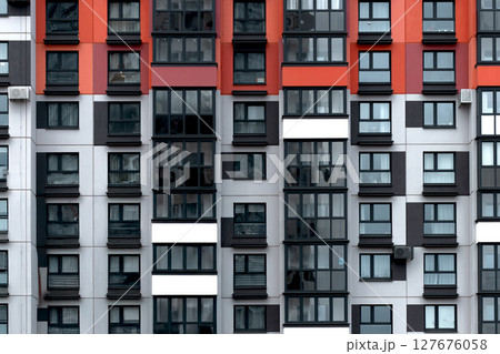 Building with red, black, and white apartment facade in geometric grid pattern. Modern modular 127676058