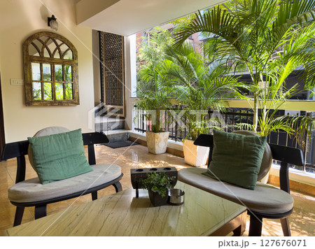 Cozy balcony with tropical plants, green foliage, and comfortable seating. Stylish veranda with 127676071