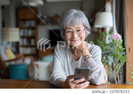 自宅でスマホを楽しむシニア女性（AI生成画像） 127676231