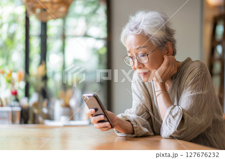 自宅でスマホを楽しむシニア女性（AI生成画像） 127676232