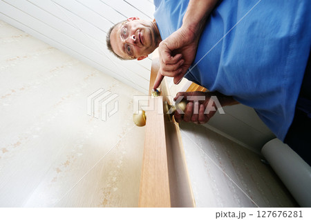 Testing latch operation by moving handle to check smooth retraction and extension of latch bolt ensuring door closes properly by installer viewed from below with wide angle. 127676281