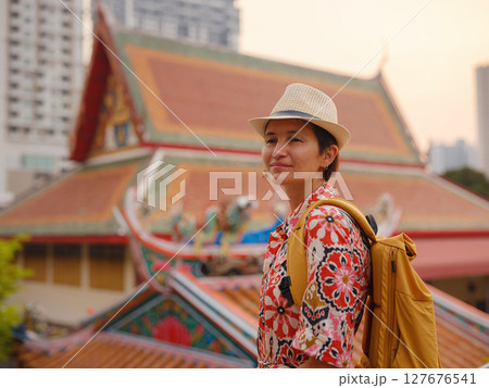 Woman Exploring Colorful Streets Near Buddhist Temples in Bangkok. Female traveler strolling through charming streets of Bangkok, surrounded by traditional architecture and beautiful Buddhist temples. 127676541