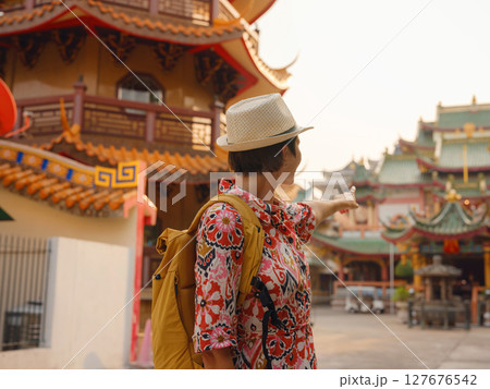 Woman Exploring Colorful Streets Near Buddhist Temples in Bangkok. Young traveler walking through the vibrant streets of Bangkok, admiring intricate temple details and lively surroundings.. 127676542