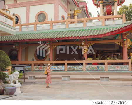 Woman Exploring Colorful Streets Near Buddhist Temples in Bangkok. Woman tourist exploring colorful alleys near historic Buddhist temples in Bangkok, enjoying the cultural atmosphere. 127676543