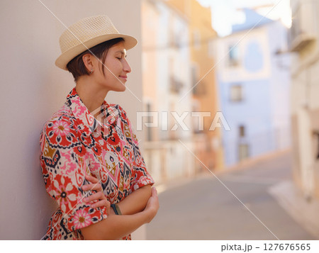 Woman in dress strolls through colorful streets of Spanish coastal town of La Vila Joiosa or Villajoyosa. sunny winter atmosphere highlights charm of Mediterranean architecture and quiet seaside life 127676565