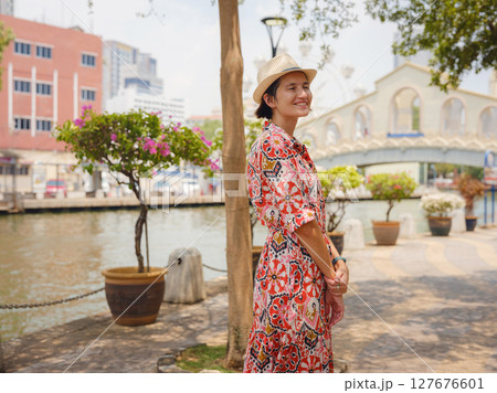 Young woman in ethnic dress and hat exploring the vibrant streets of Malacca, Malaysia. A blend of cultural heritage, colorful architecture, and tropical charm. Perfect travel and lifestyle moments. Young woman in ethnic dress and hat exploring the vibrant streets of Malacca, Malaysia. A blend of cultural heritage, colorful architecture, and tropical charm. Perfect travel and lifestyle moments. 127676601