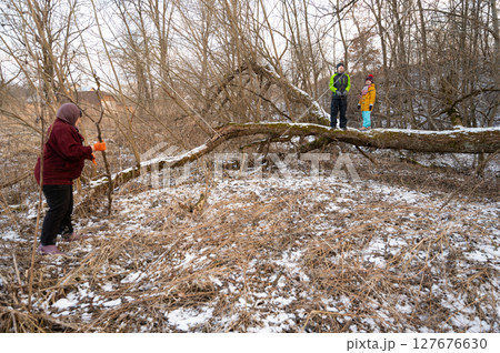 Winter adventure unfolds in a snowy landscape where friends explore nature while one person carefully climbs a fallen tree under the watchful eye of their companions Winter adventure unfolds in a snowy landscape where friends explore nature while one person carefully climbs a fallen tree under the watchful eye of their companions 127676630