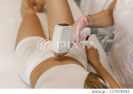 Hair removal procedure. Cropped shot of young fit woman client receiving laser hair removal procedure on body in beauty clinic. Women beauty and cosmetology concept 127676983